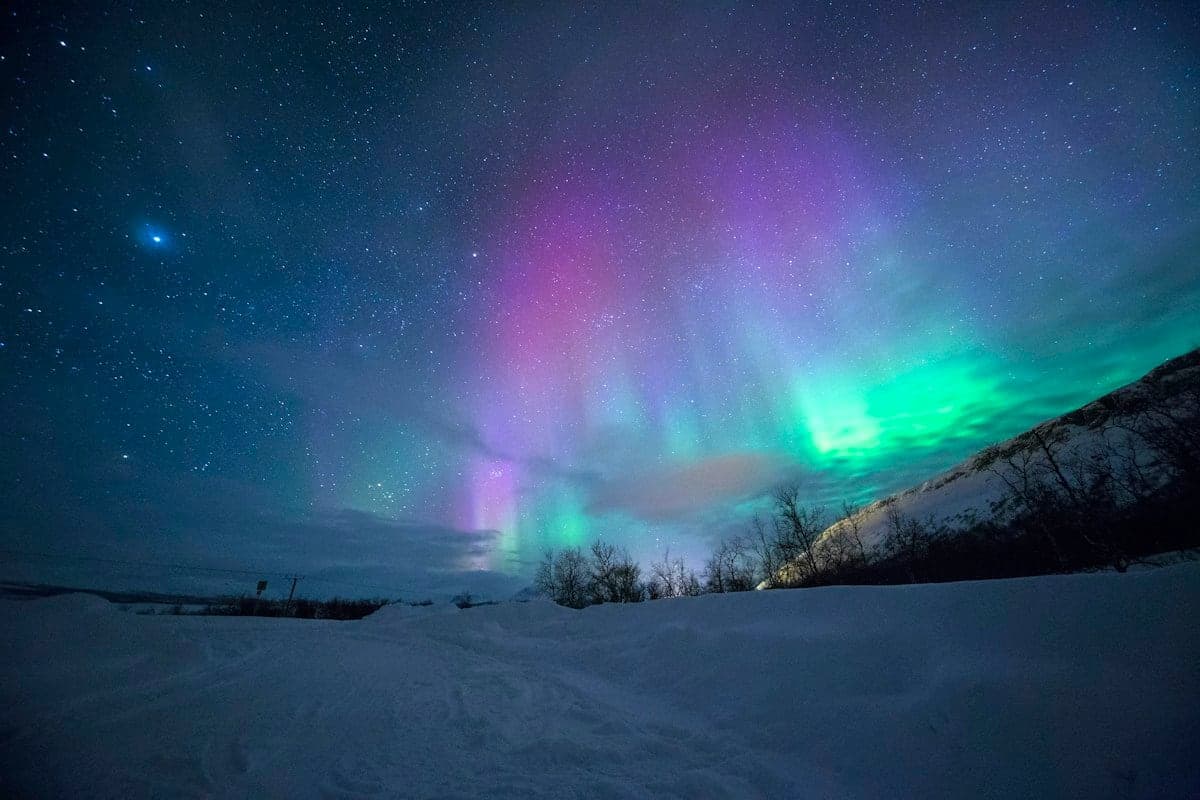 Tromsø Northern Lights aurora borealis dancing over snow-covered Arctic fjords
